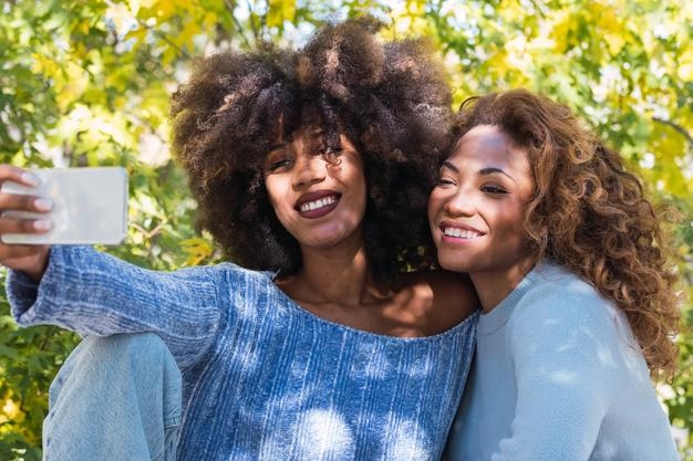 Cheerful female friends doings selfie outdoors