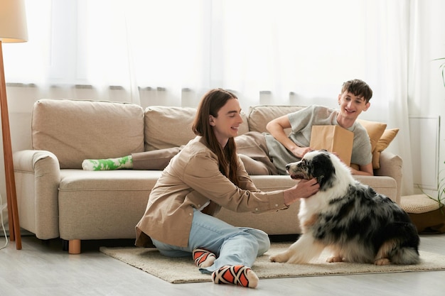 cheerful gay man with long hair playing with australian shepherd dog while his boyfriend in casual