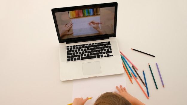 Child learns to draw from a tutorial on a laptop