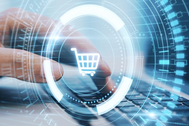 close up hand typing on laptop keyboard with creative glowing blue cart hologram on dark background online shopping and purchase concept double exposure