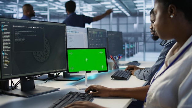 Close up of coworkers coding on chroma key device in data center