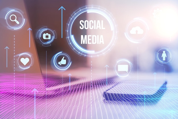 Close up of desk with laptop smartphone and glowing social media hologram on blurry background Likes shares and network concept Toned image Double exposure