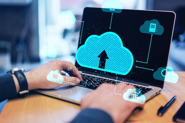 Close up of male hands using laptop at desktop with abstract digital cloud on blurry background Cloud computing database and technology concept