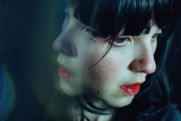 Close-up of woman by glass in darkroom