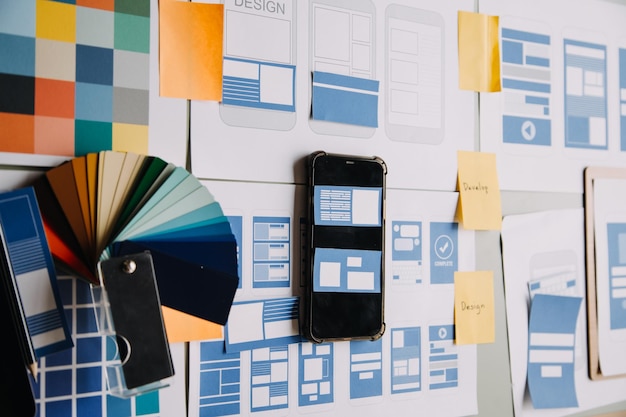 close up ux developer and ui designer brainstorming about mobile app interface wireframe design on table with customer breif and color code at modern officecreative digital development agency
