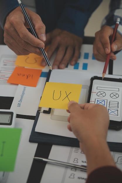 Close up ux developer and ui designer brainstorming about mobile app interface wireframe design on table with customer breif and color code at modern officeCreative digital development agency