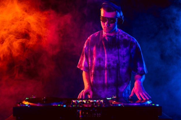 Club DJ playing music at party wearing sunglasses