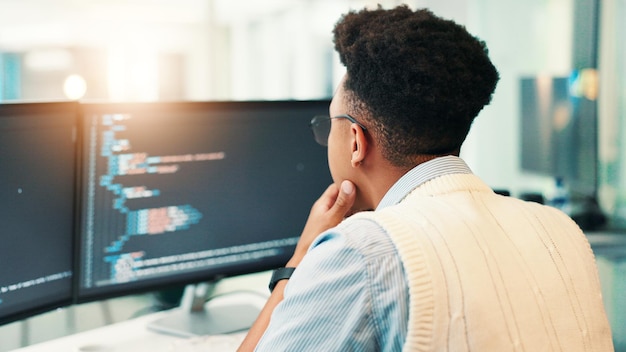 Coding man and computer screen with thinking in office for programming solution app development and debugging Back coder and data analytics for software testing system update and problem solving