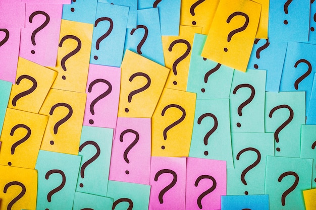 colorful paper notes with question marks surface. closeup top view toned.