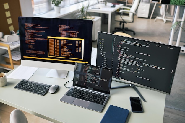 Computers and laptop on office desk of software developer