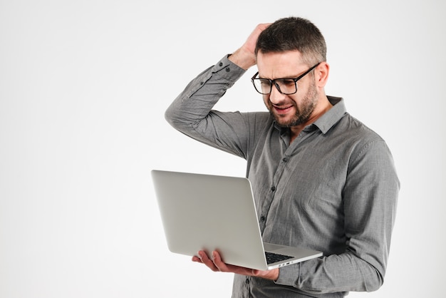 Confused businessman using laptop computer.