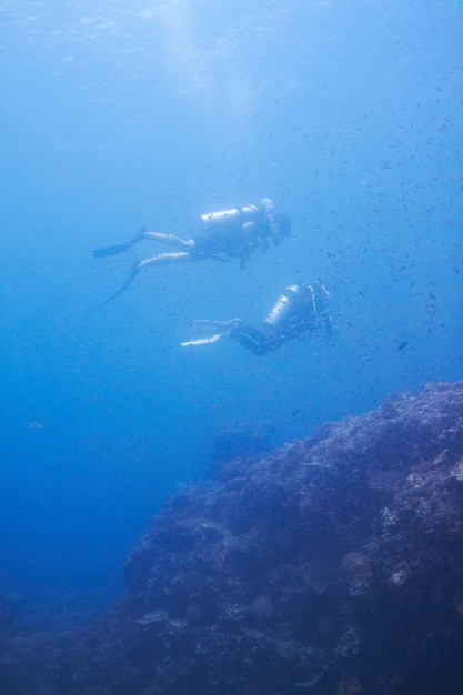 couple swimming and scuba diving in sea for underwater adventure and explore on tropical holiday or vacation sports people tourist or diver with bubbles blue water and search ocean life or coral