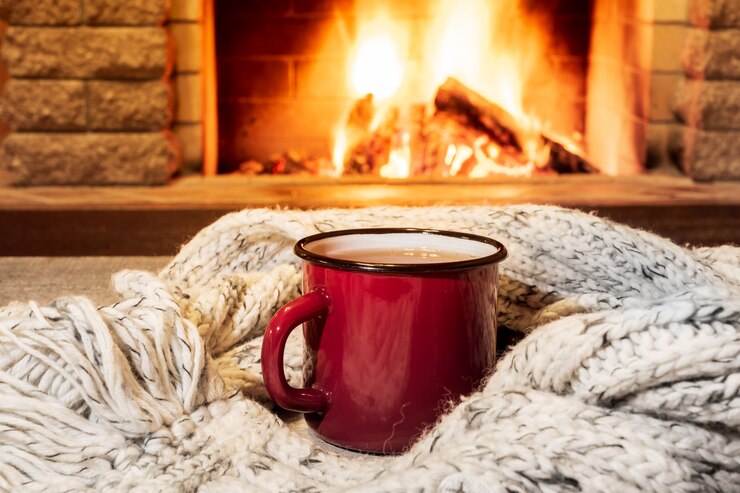 Foto cozy scene near fireplace with a red enameled mug with hot tea and cozy warm scarf.