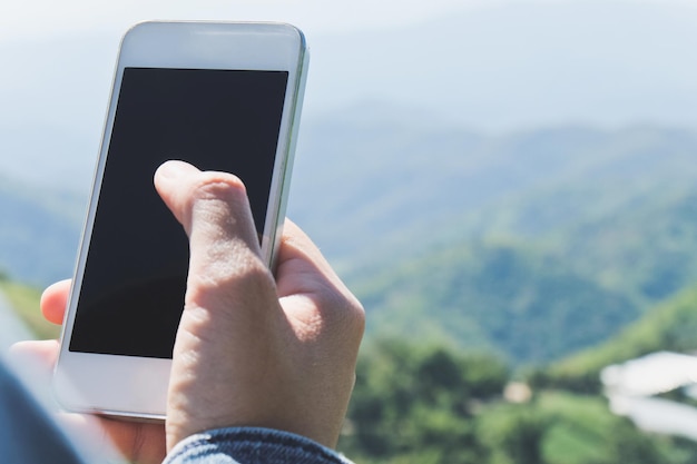 Cropped hand of man using mobile phone against sky