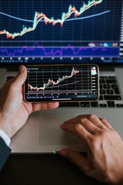 cropped hands of businessman holding smart phone and using laptop