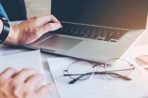 Cropped hands of businessman using laptop on desk