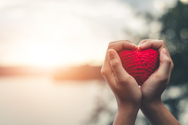 Cropped hands of person holding heart shape against sky