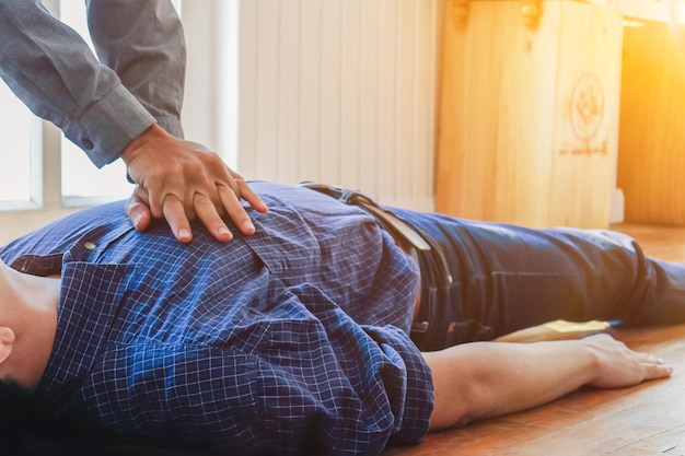 Cropped hands performing cpr on man lying on floor