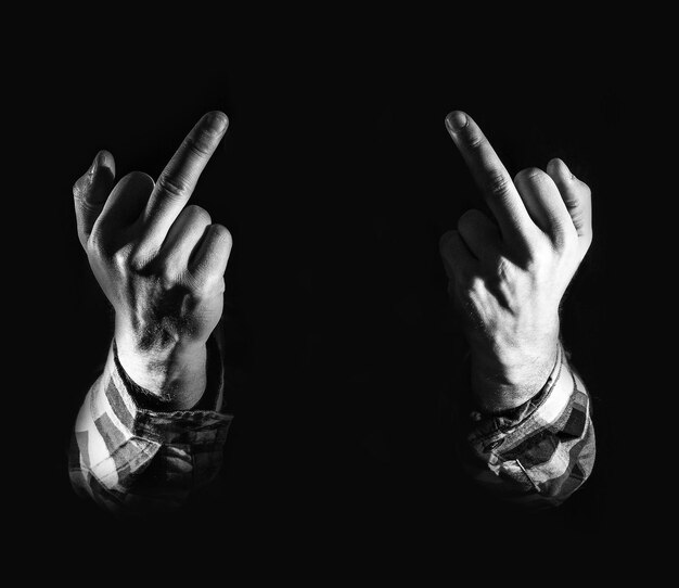 Cropped image of person showing obscene gesture in darkroom