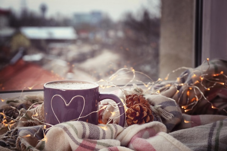 Foto cup of hot tasty coffee with garland and warm plaid on windowsill