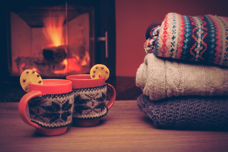 Foto cup with christmas ornament near fireplace mug in red knitted mitten standing near fireside