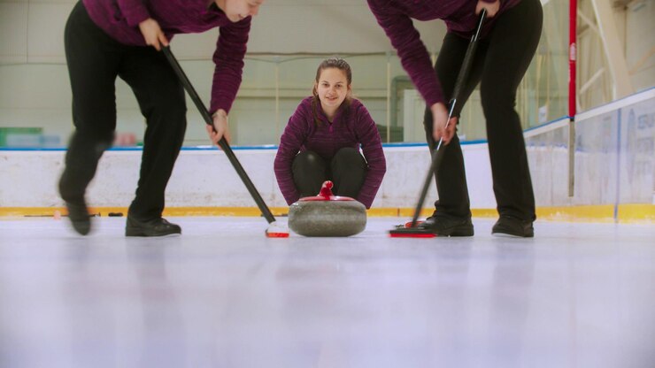 Foto curling  leading granite stone on the ice and rubbing the ice before the stone