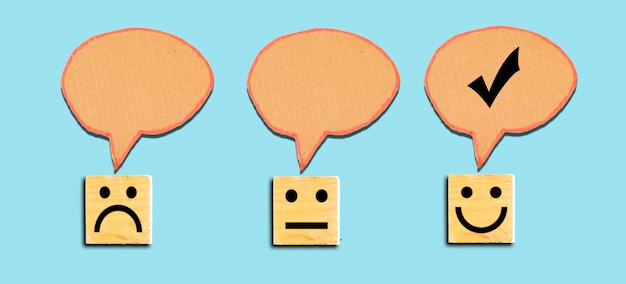 Customer service evaluation and satisfaction survey concepts Face icon on wooden cube and chat bubb