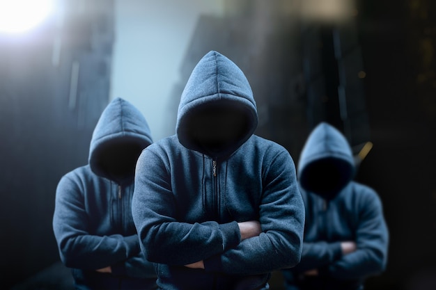 dangerous criminal scary hooded guys at night in dark alley silhouette bandit criminal with an unrecognizable face in threatening pose at night on dark street