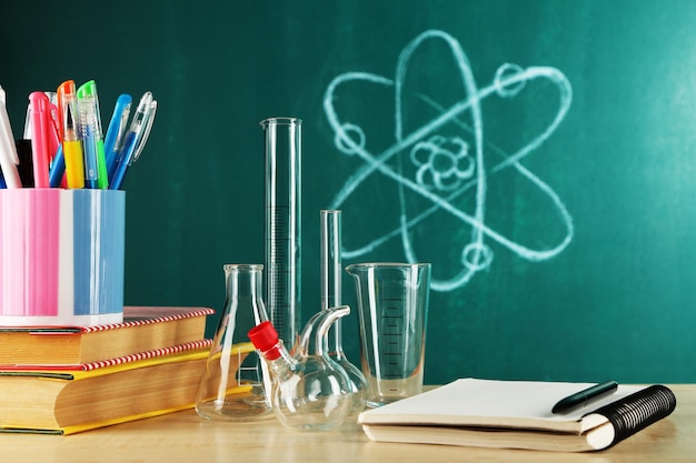 Desk in chemistry class with test tubes on green blackboard background