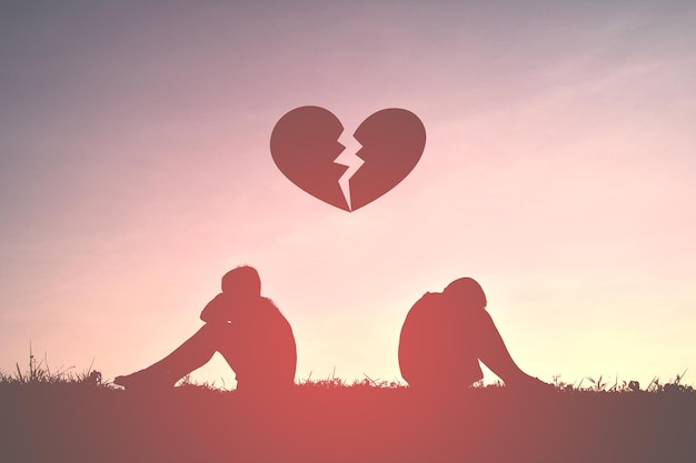 Digital composite image of broken heart over silhouette boys on field against sky during sunset