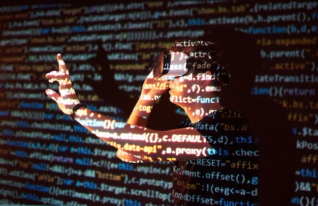 Double exposure of a caucasian man and Virtual reality headset is presumably a gamer or a hacker cracking the code into a secure network or server with lines of code