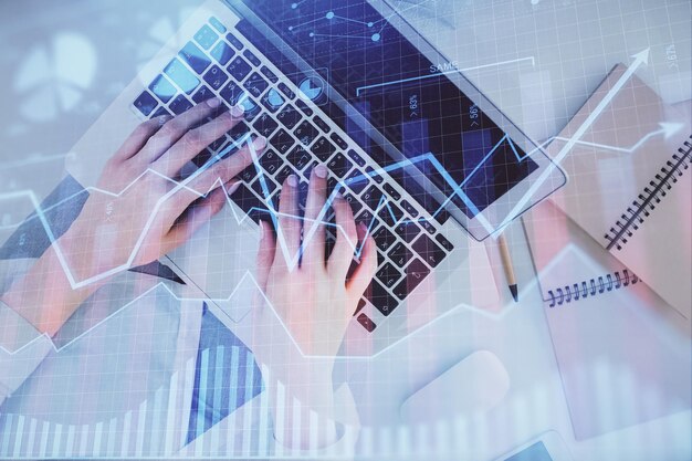 Double exposure of woman hands working on computer and forex graph hologram drawing Top View Financial analysis concept