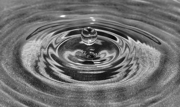 Drop of water falling into the water itself and creating ripples.