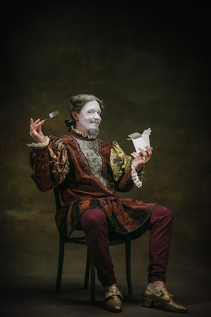 Eating an oyster Young man as Johann Bach isolated on dark green background