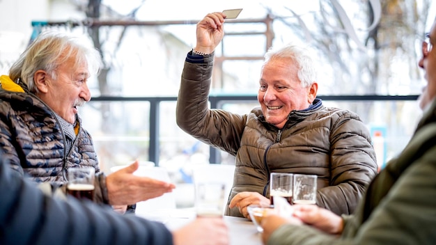 Eldre venner som spiller kort på lokal bar på en vinterdag