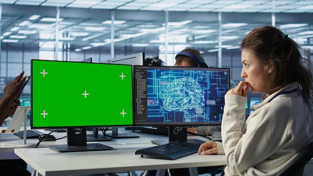 Employee works on green screen computer in server hub using AI to process data