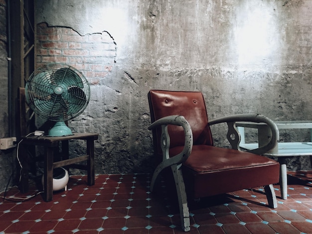 empty armchair by electric fan in old room