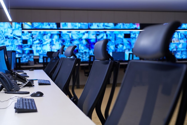 empty interior of big modern security system control room, workstation with multiple displays, monitoring room with at security data center  empty office, desk, and chairs at a main cctv security data