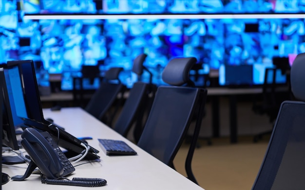 empty interior of big modern security system control room, workstation with multiple displays, monitoring room with at security data center  empty office, desk, and chairs at a main cctv security data