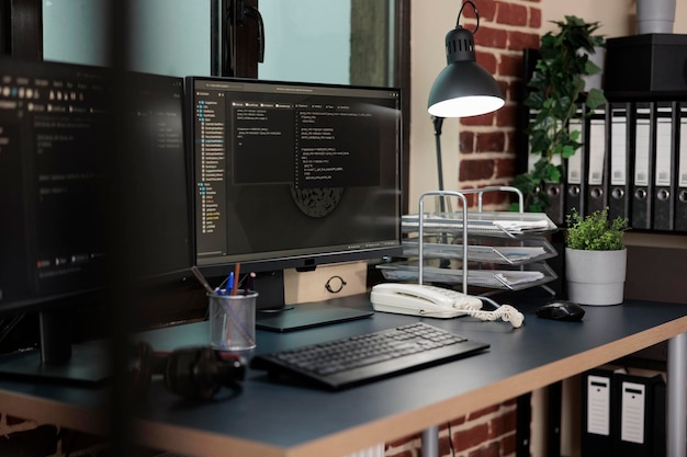 empty office with nobody in it containing multiple displays showing system programming language. image of two computer screens displaying software data information and integrated algorithms.