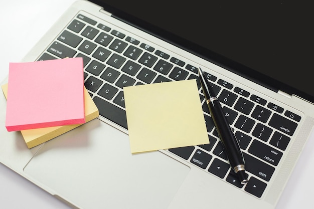 Empty sticky post note paper sheet and pen on laptop keyboard. note list, message memory.