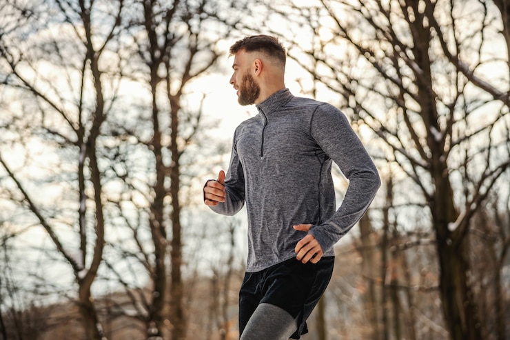 Foto fit sportsman jogging in nature at snowy winter day. cold weather, winter fitness, cardio exercises