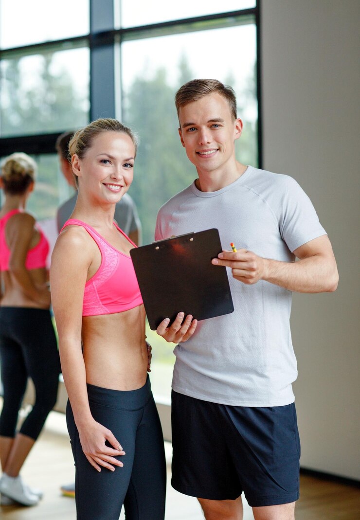 Foto fitness, sport, exercising and diet concept - smiling young woman with personal trainer in gym