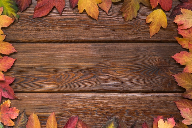flat lay with autumn leaves border frame on rustic dark wooden background. 