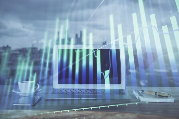 Forex graph hologram on table with computer background Multi exposure Concept of financial markets