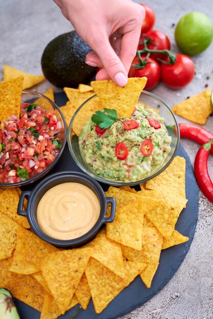 Freshly made salsa and guacamole dip sauce with nacho chips on stone serving board