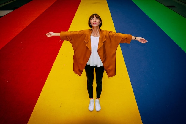 Full length portrait of woman standing against colourful floor