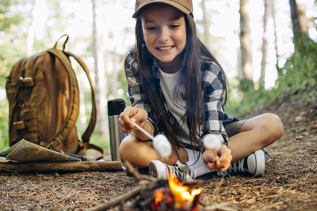 Girl scout frying marshmallows on fire at the woods