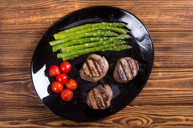 Grilled filet mignon with asparagus and tomatoes Beef sreak on rustic background