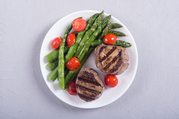 Grilled filet mignon with asparagus and tomatoes Beef sreak on rustic background